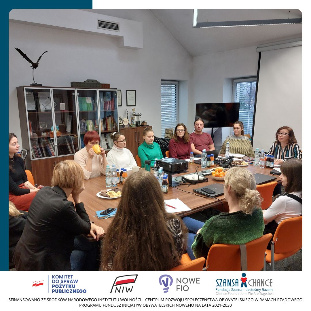 Grupa osób siedzi w sali konferencyjnej i słucha prezentacji kobiety.